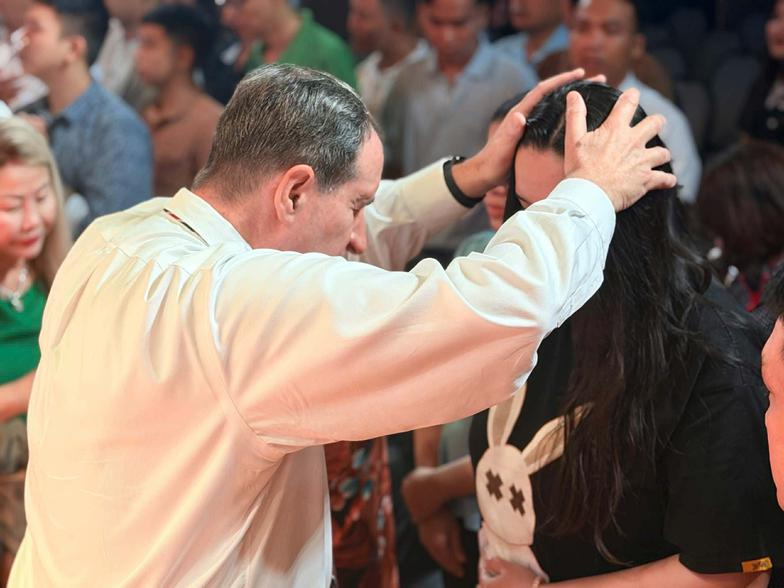 Pastor Bill Marshall praying for a woman during a church service